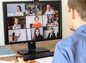 Virtual conference with employees. A young man in formal shirt using pc for video call, he has video meeting with several people together. Remote work concept